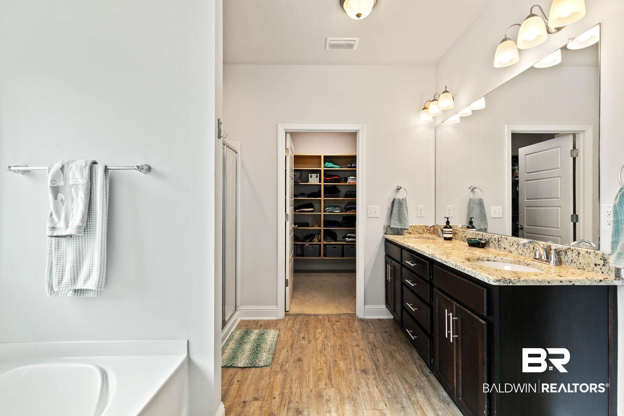 31350 Hoot Owl Road Daphne, AL 36527 - Photo 28 of 94 Full bathroom featuring a walk in closet, double vanity, a garden tub, light wood finished floors, and a stall shower