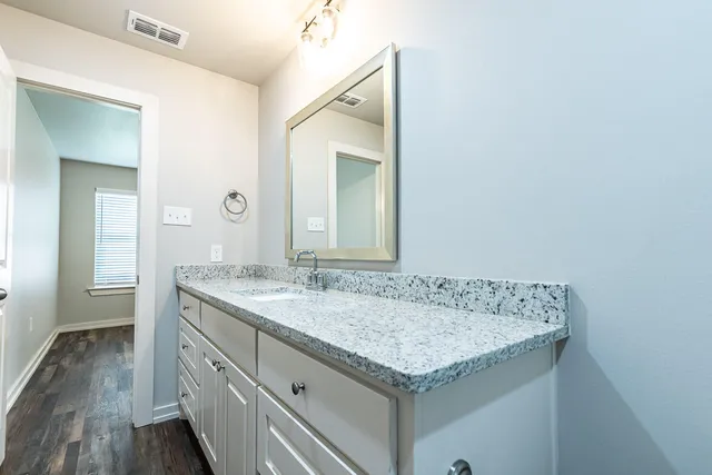 a bathroom with a granite countertop sink and a mirror