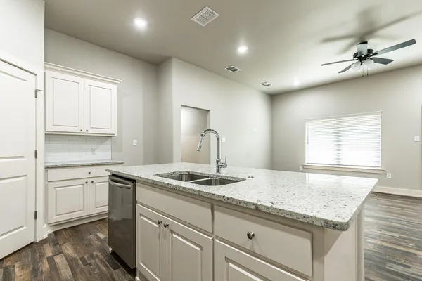 a kitchen with kitchen island granite countertop a sink cabinets and wooden floor