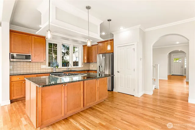a large kitchen with stainless steel appliances granite countertop a stove a sink and a refrigerator
