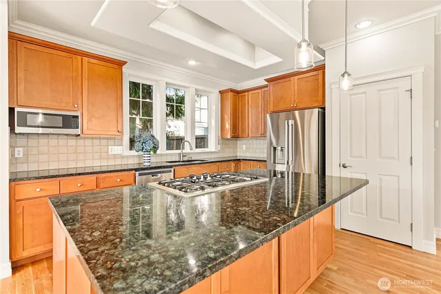 a kitchen with stainless steel appliances granite countertop a refrigerator a stove and white cabinets with wooden floor