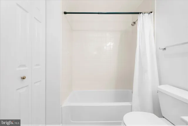 a view of a big room with wooden floor a ceiling fan and windows