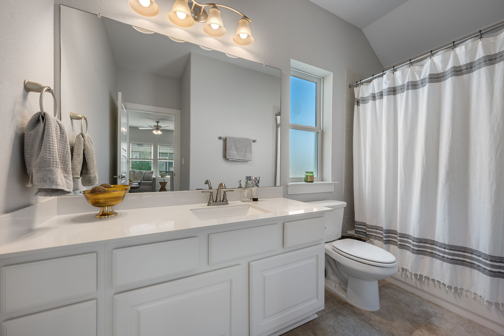 5409 Fox Wing Way Austin, TX 78747 - Photo 19 of 26 A well-lit bathroom with a bright window, a clean white vanity, and practical tile flooring.