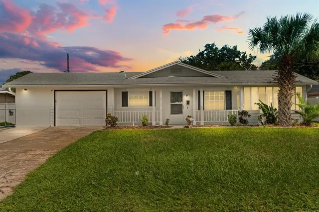 a front view of a house with a yard and palm trees