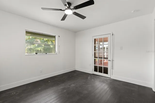 an empty room with wooden floor fan and windows
