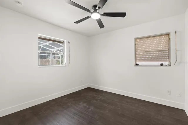 an empty room with a window and a ceiling fan