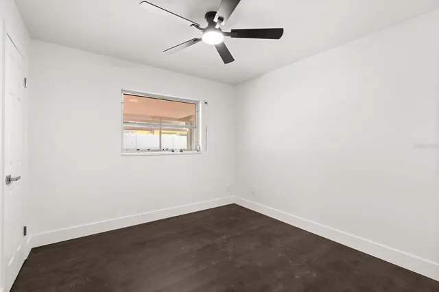an empty room with a window and a fan