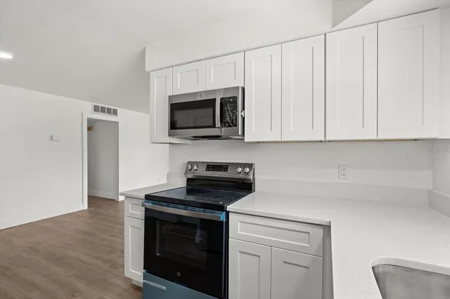 a kitchen with white cabinets stainless steel appliances and wooden floor
