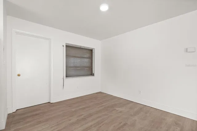 a view of an empty room with wooden floor and closet