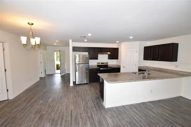 a large white kitchen with a large counter top stainless steel appliances and wooden floor
