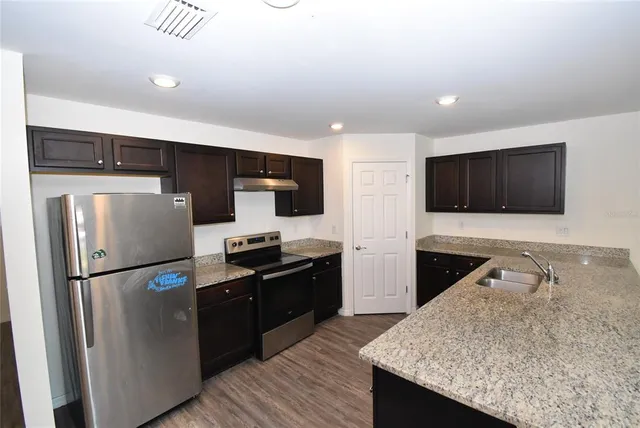 a kitchen with stainless steel appliances granite countertop a refrigerator a stove a sink and a microwave