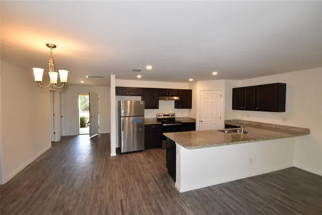 a large kitchen with a large counter top stainless steel appliances and wooden floor