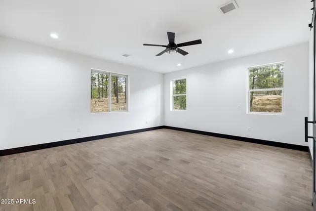 a view of an empty room with a window and wooden floor
