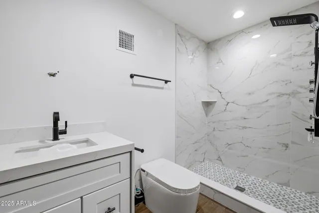 a bathroom with a granite countertop toilet sink and mirror