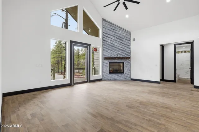 an empty room with chandelier fan and windows