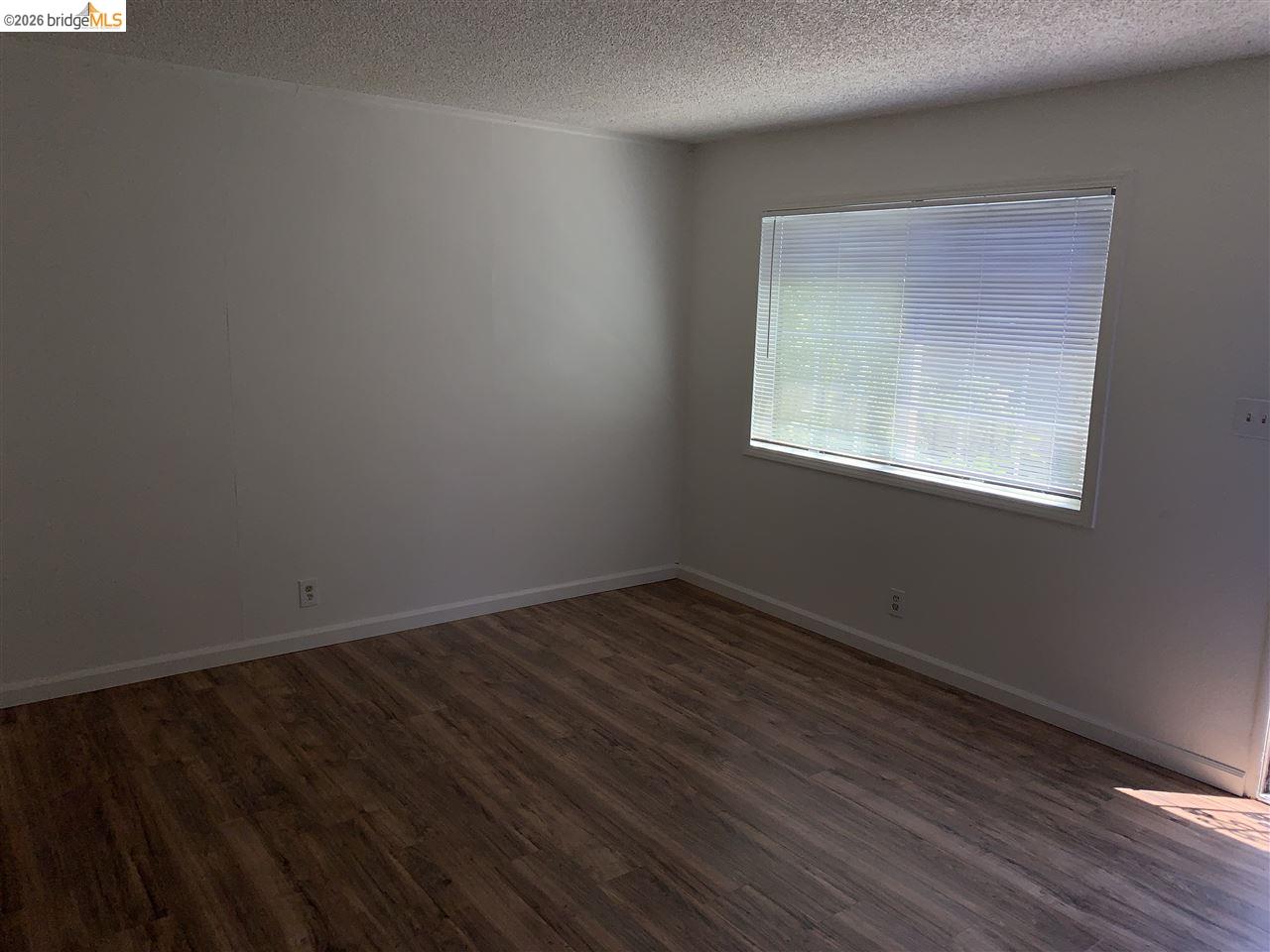 124 West 8th Street, Unit B Tracy, CA 95376 - Photo 8 of 11 an empty room with wooden floor and windows