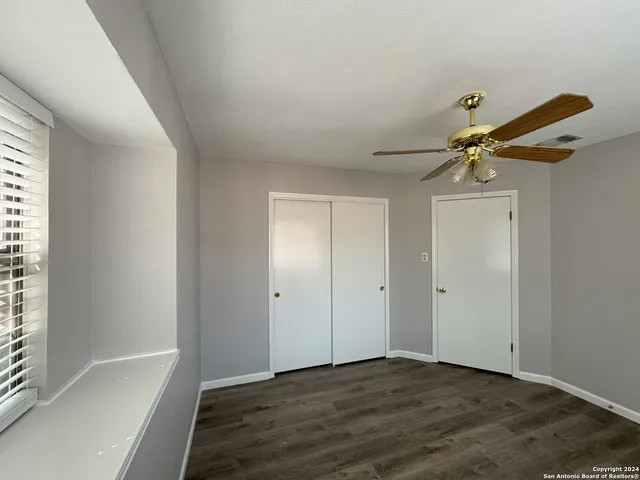 a view of empty room with wooden floor and fan