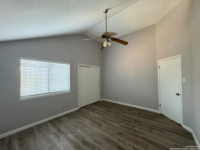 a view of empty room with wooden floor and fan