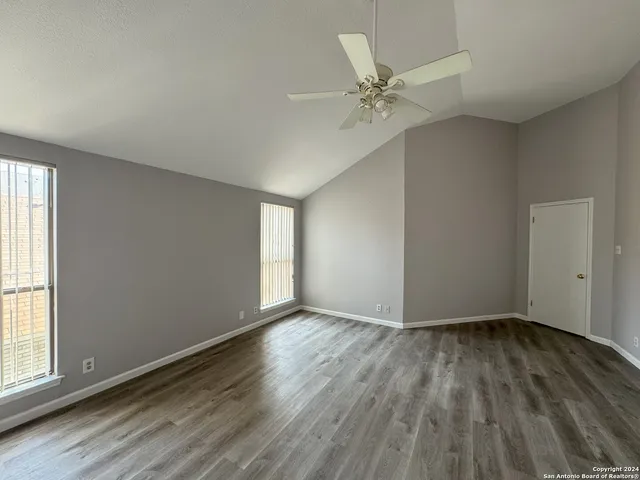 a view of an empty room with wooden floor and a window