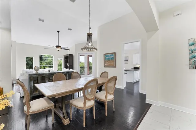 a kitchen with stainless steel appliances granite countertop a dining table chairs refrigerator and sink