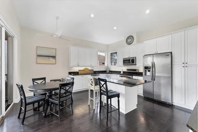 a kitchen with sink stove and white cabinets with wooden floor