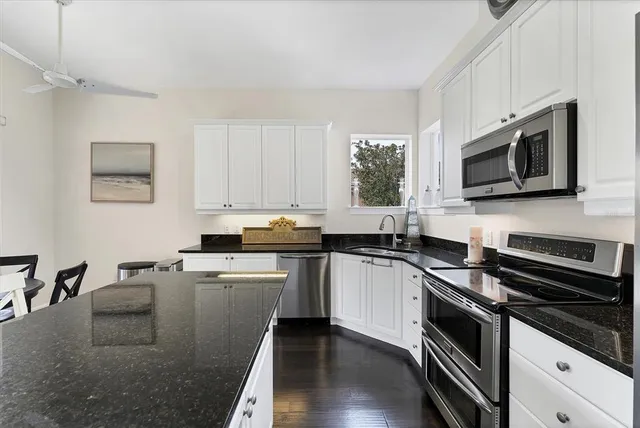 a kitchen with granite countertop a stove a refrigerator and a sink
