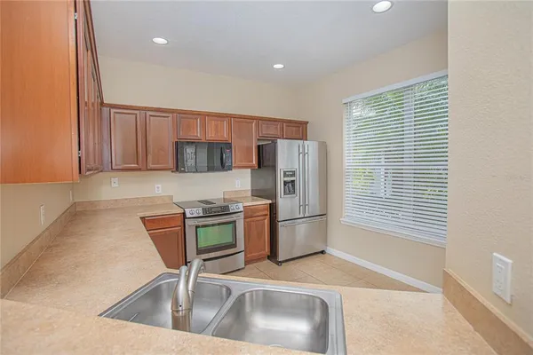 a kitchen with stainless steel appliances a sink a stove a microwave a refrigerator and cabinets