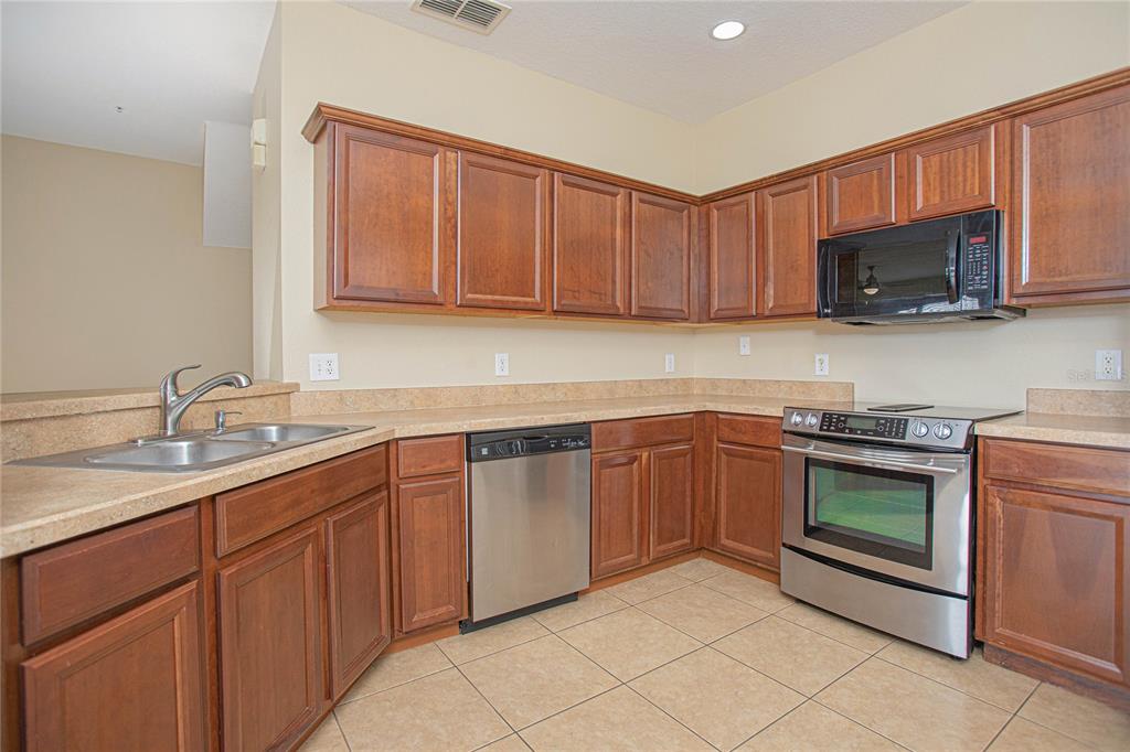 6468 South Goldenrod Road, Unit 34B Orlando, FL 32822 - Photo 13 of 34 a kitchen with stainless steel appliances granite countertop a sink a stove a microwave and cabinets