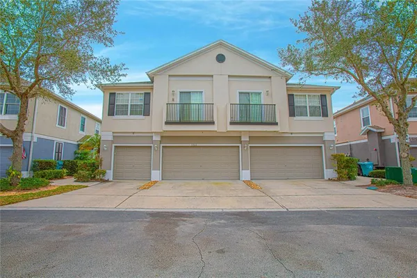 a view of yellow house with a large windows and large tree