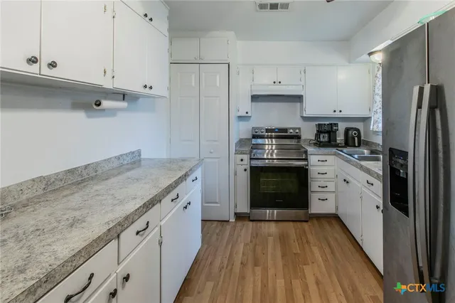 a kitchen with granite countertop white cabinets and stainless steel appliances