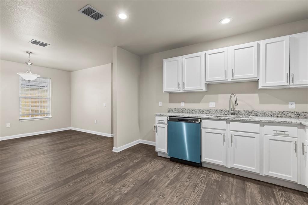 2723 Parsons Street Dallas, TX 75215 - Photo 11 of 28 a kitchen with granite countertop wooden floors white cabinets and stainless steel appliances