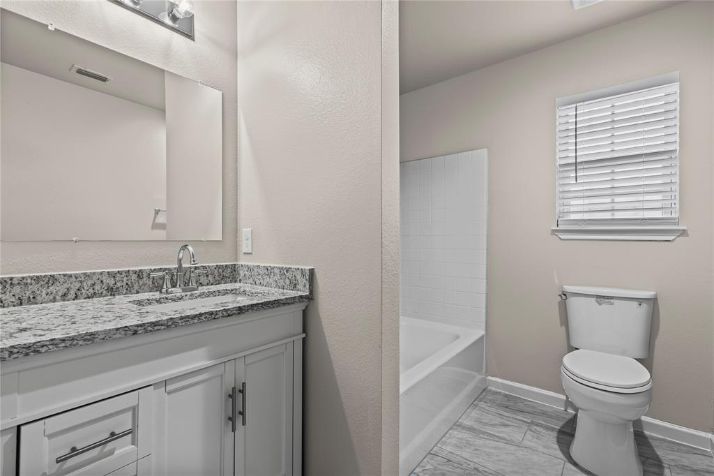 2723 Parsons Street Dallas, TX 75215 - Photo 14 of 28 a bathroom with a granite countertop toilet a sink and a bathtub