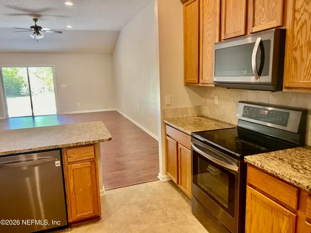 a kitchen with granite countertop a stove a sink and a microwave
