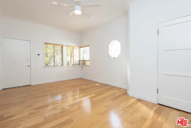 a view of an empty room with wooden floor and a window