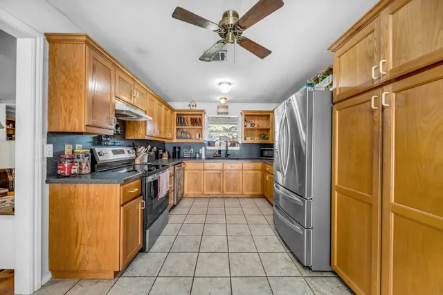 a kitchen with stainless steel appliances granite countertop a refrigerator a sink dishwasher a stove and a refrigerator
