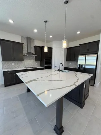 a large kitchen with stainless steel appliances kitchen island granite countertop a stove a sink dishwasher a refrigerator and a kitchen island with wooden floor