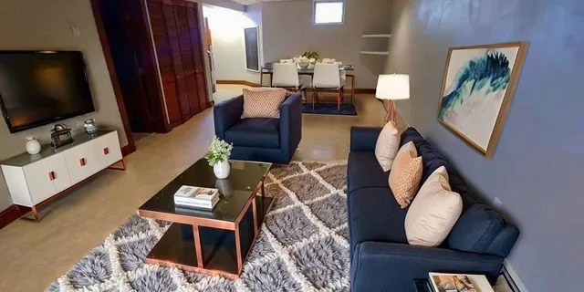 a living room with furniture a flat screen tv and a floor to ceiling window