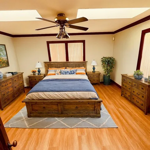 a bedroom with a bed and a dresser with wooden floor