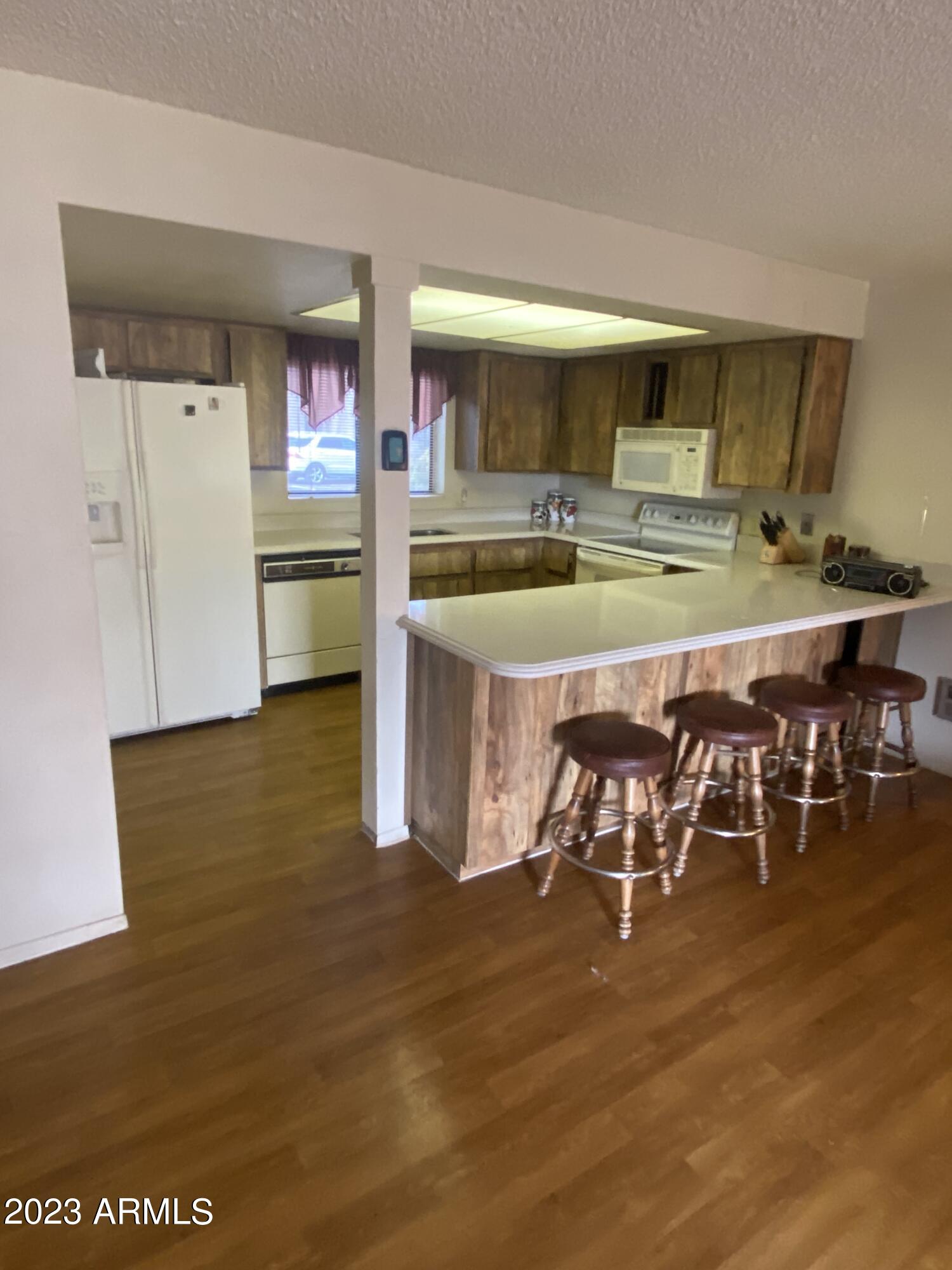 17980 Walapai Road, Unit 19A Munds Park, AZ 86017 - Photo 18 of 32 a kitchen with stainless steel appliances granite countertop a stove top oven a sink a dining table and chairs with wooden floor