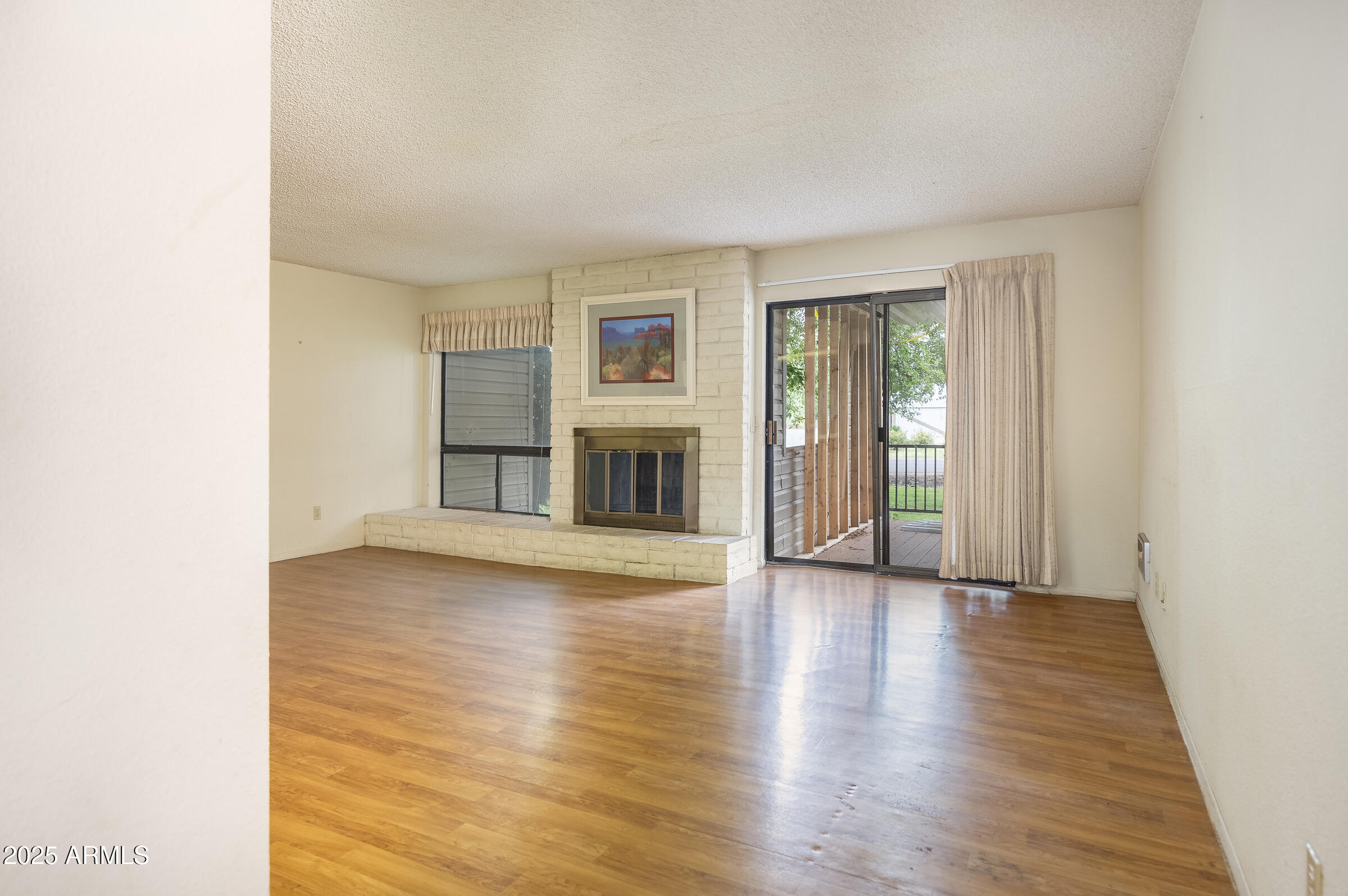 17980 Walapai Road, Unit 19A Munds Park, AZ 86017 - Photo 9 of 32 an empty room with wooden floor fireplace and windows