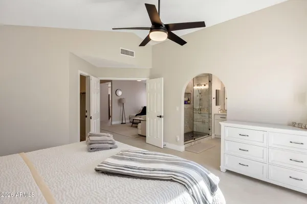 a bedroom with a large bed and ceiling fan