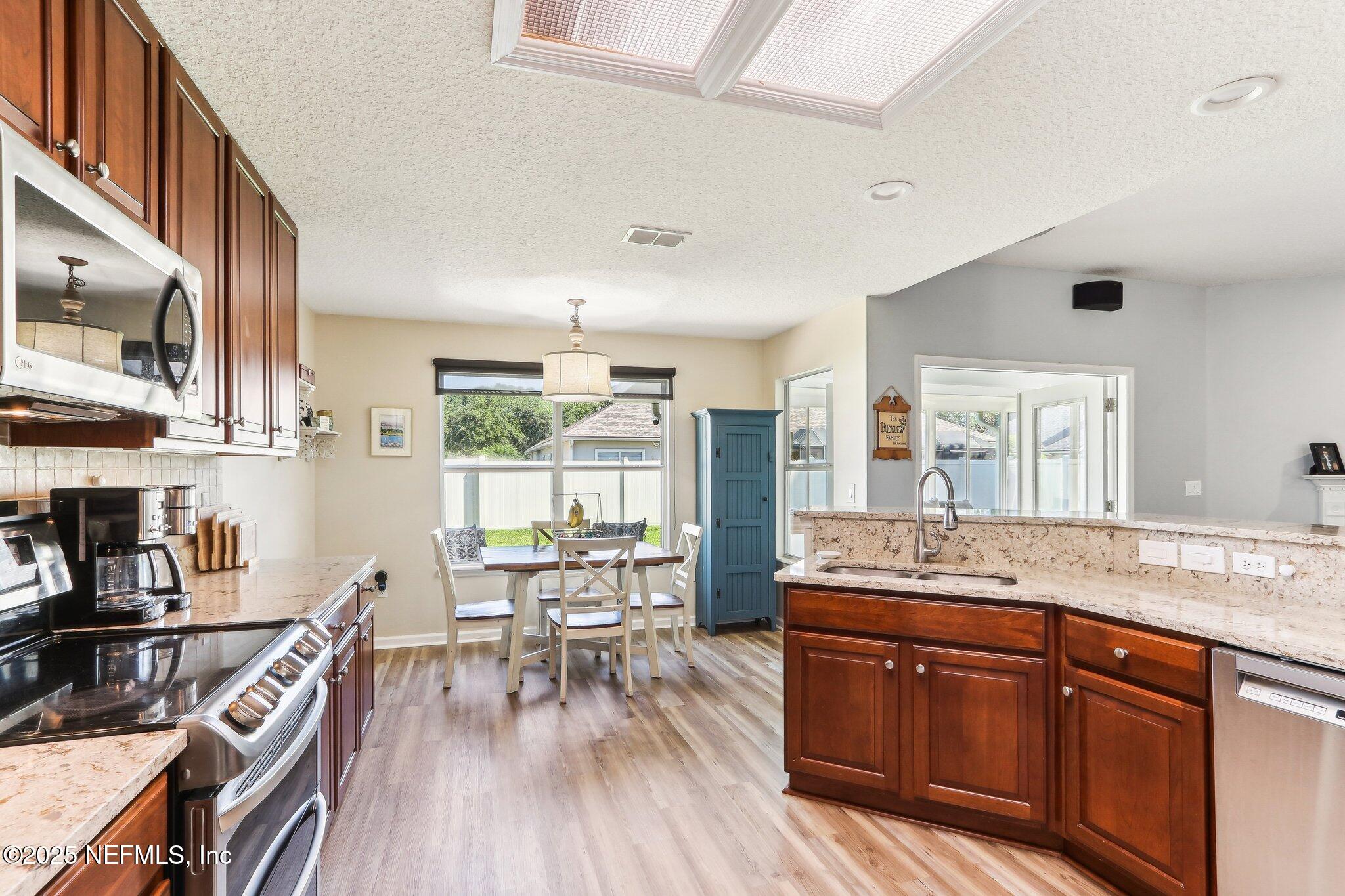 2124 Pond Spring Way Fleming Island, FL 32003 - Photo 14 of 56 a large kitchen with stainless steel appliances granite countertop a lot of counter space and a wooden floors