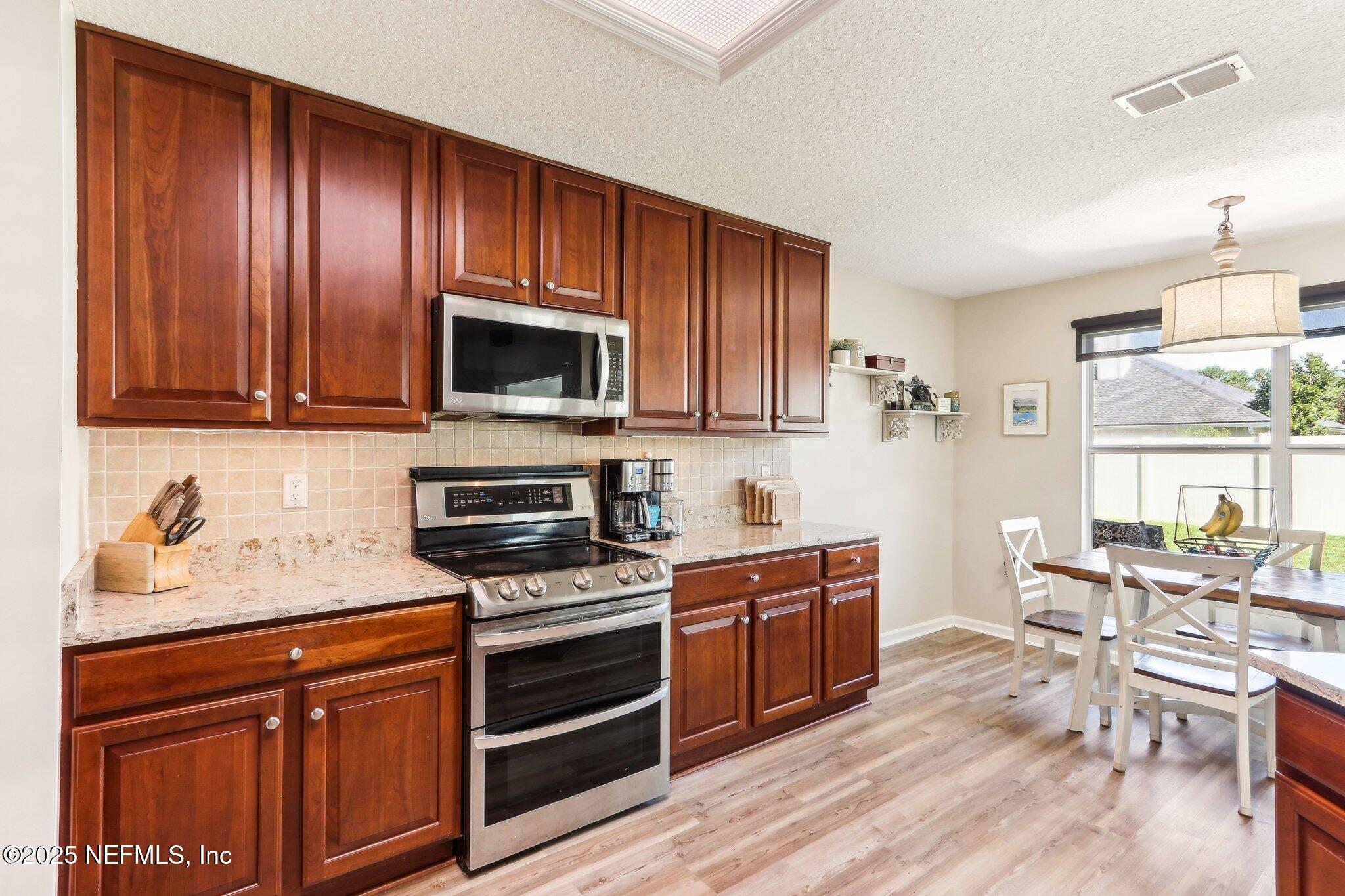 2124 Pond Spring Way Fleming Island, FL 32003 - Photo 15 of 56 a kitchen with stainless steel appliances granite countertop wooden cabinets a stove a sink and dishwasher with wooden floor