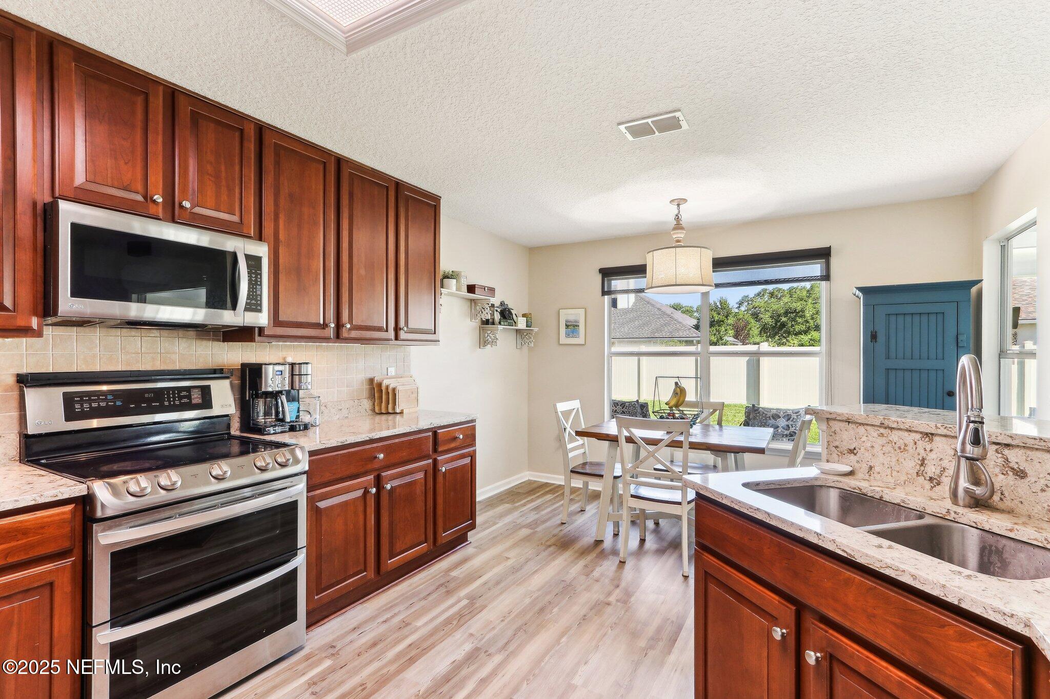 2124 Pond Spring Way Fleming Island, FL 32003 - Photo 16 of 56 a kitchen with stainless steel appliances a stove sink microwave and cabinets