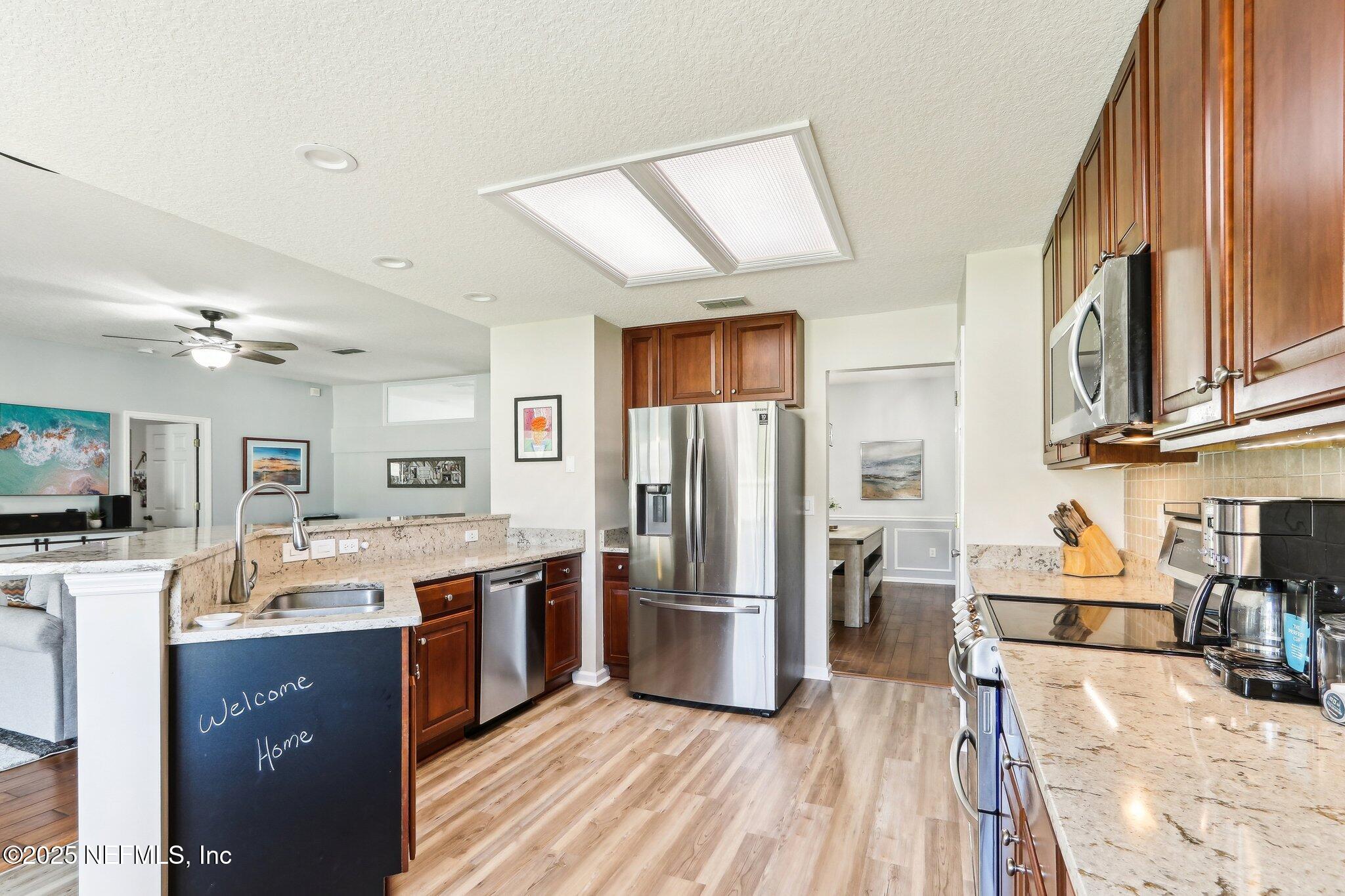 2124 Pond Spring Way Fleming Island, FL 32003 - Photo 18 of 56 a kitchen with stainless steel appliances granite countertop a refrigerator a stove top oven a sink dishwasher and wooden cabinets with large window