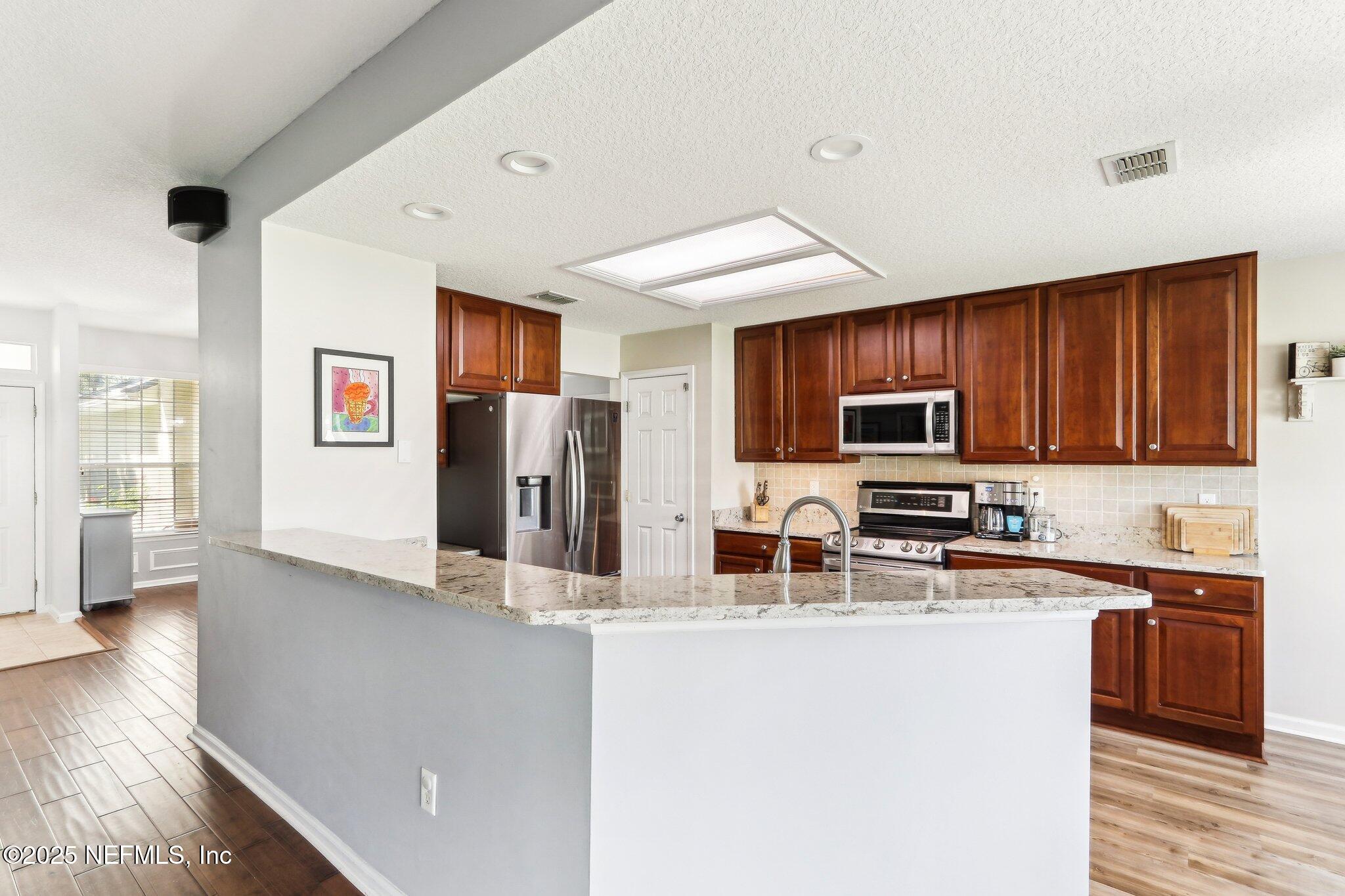 2124 Pond Spring Way Fleming Island, FL 32003 - Photo 19 of 56 a kitchen with stainless steel appliances a refrigerator stove microwave and sink