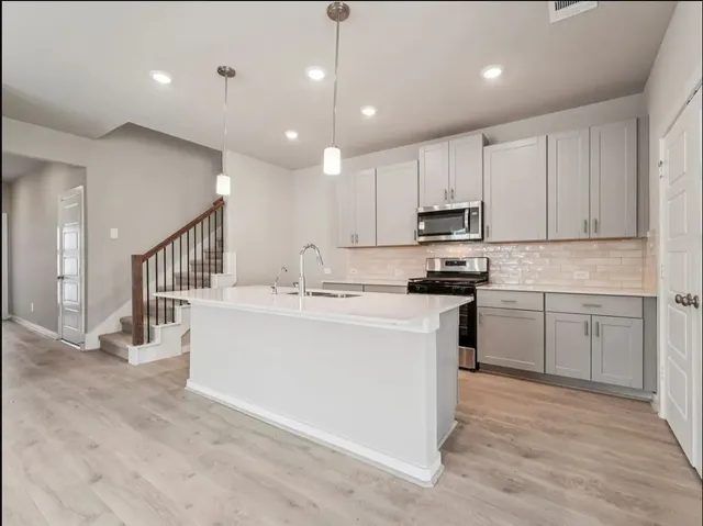 a kitchen with kitchen island sink stove and cabinets