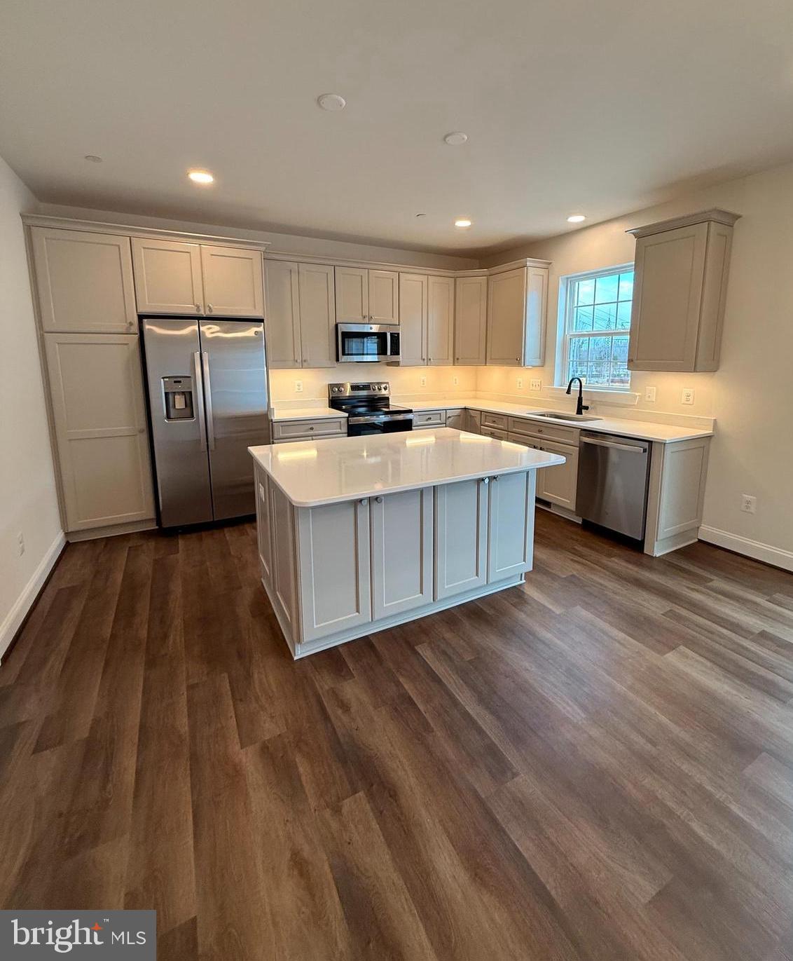 a large white kitchen with sink and refrigerator