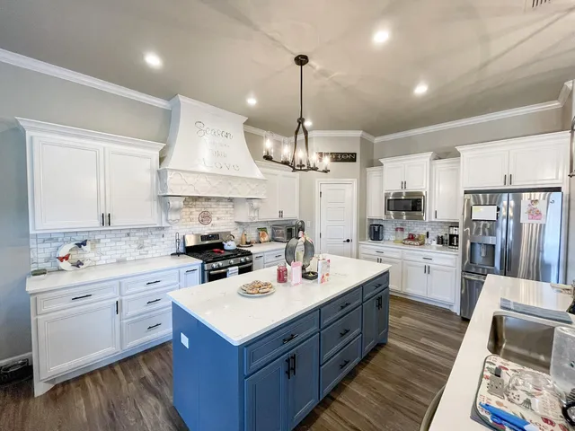 a kitchen with a sink stove cabinets and wooden floor