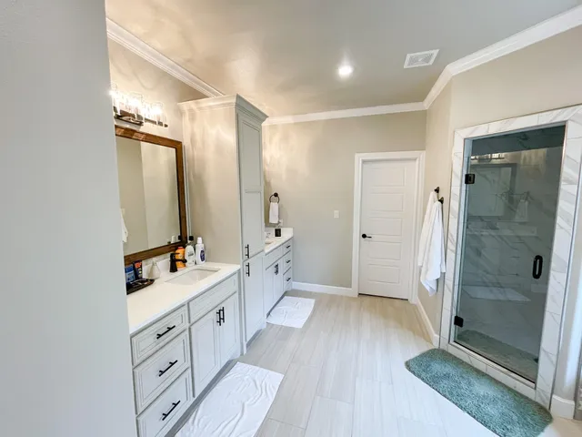 a spacious bathroom with a double vanity sink a mirror and a shower